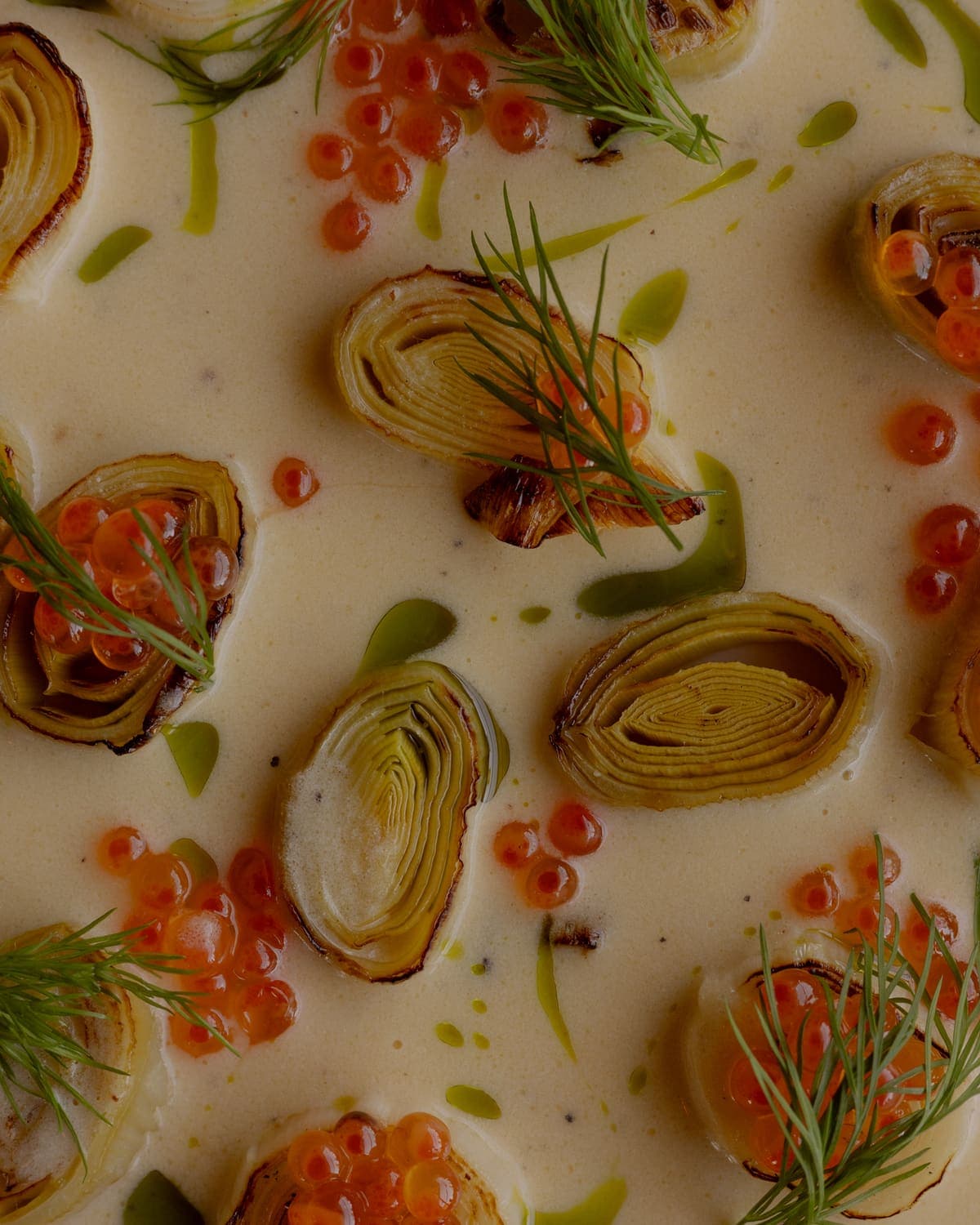 Charred leeks with salmon roe and herb oil on a cream sauce