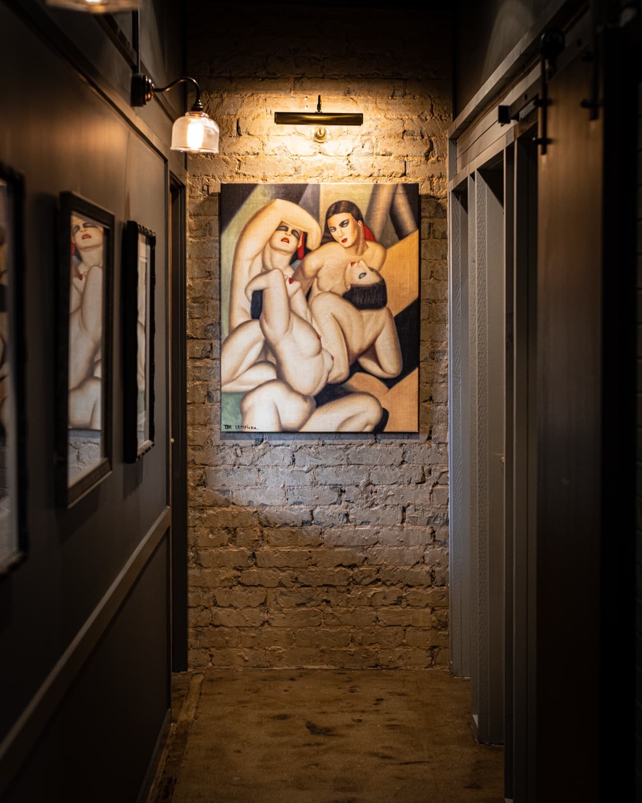 Wakefield's brick corridor, lamplit, hung with art-deco paintings